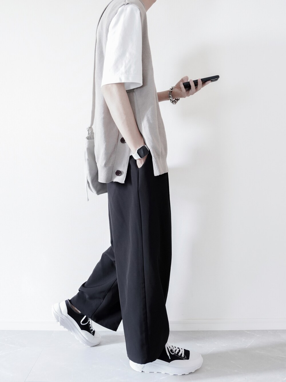 ベージュ系のベスト、ホワイト系のTシャツ/カットソー、ブラック系のスラックスを着用したメンズの春コーディネートの2枚目の写真