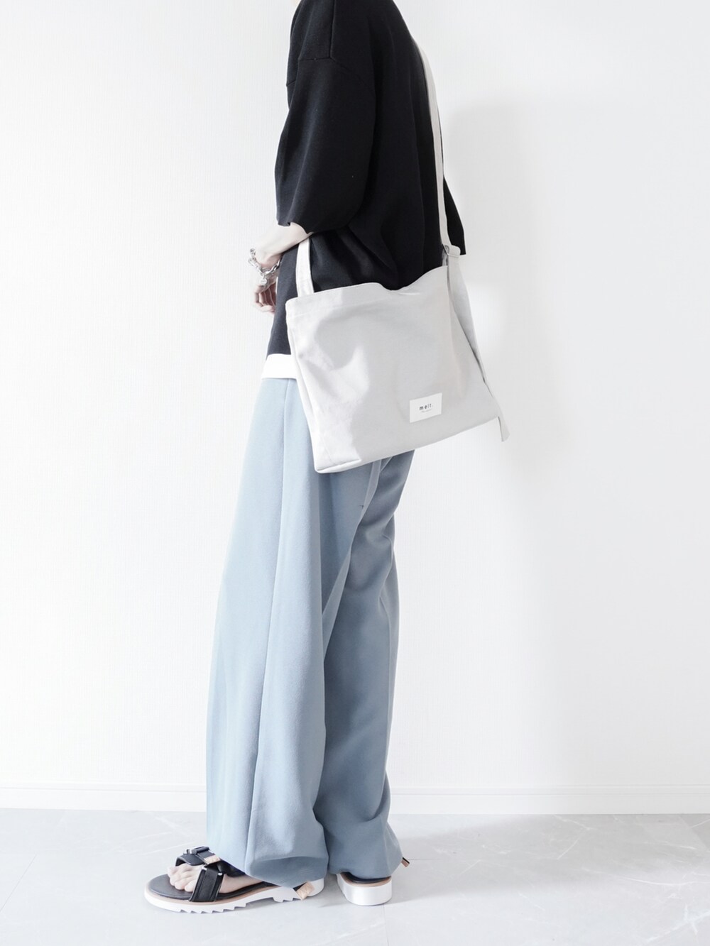 ブラック系のポロシャツ、ホワイト系のタンクトップ、ブルー系のスラックスを着用したメンズの春コーディネートの3枚目の写真