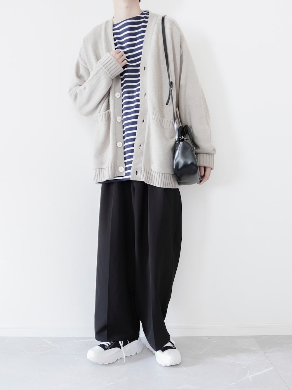 ベージュ系のカーディガン/ボレロ、ブルー系のTシャツ/カットソー、ブラック系のスラックスを着用したメンズの春コーディネートの2枚目の写真