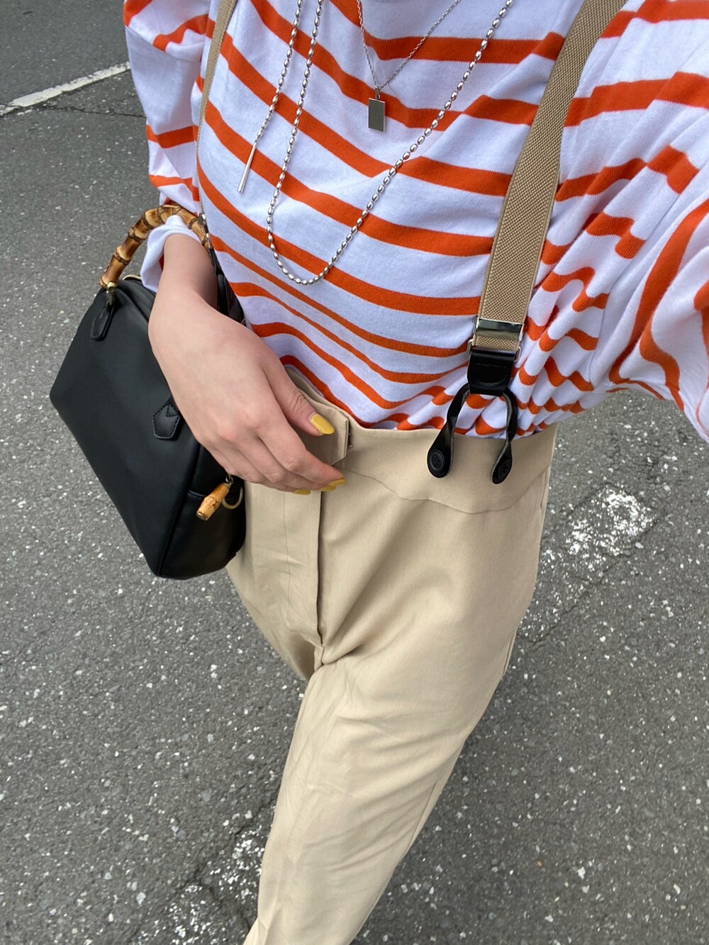 オレンジ系のトップスを着用したレディースの春コーディネートの2枚目の写真