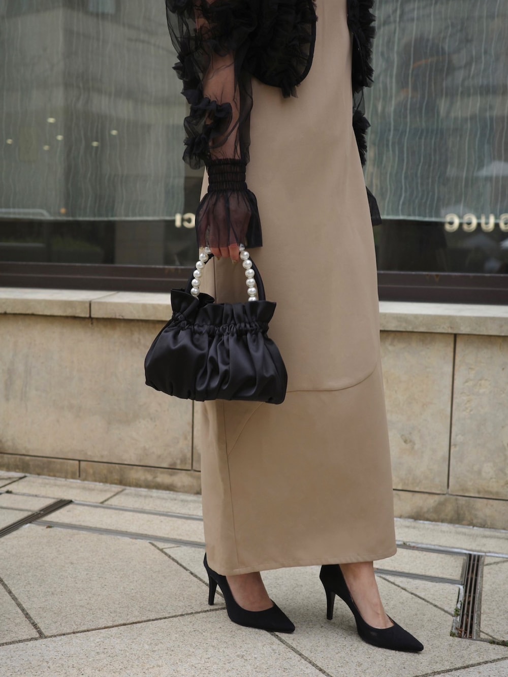 ベージュ系のドレス、ブラック系のハンドバッグを着用したレディースの春コーディネートの2枚目の写真