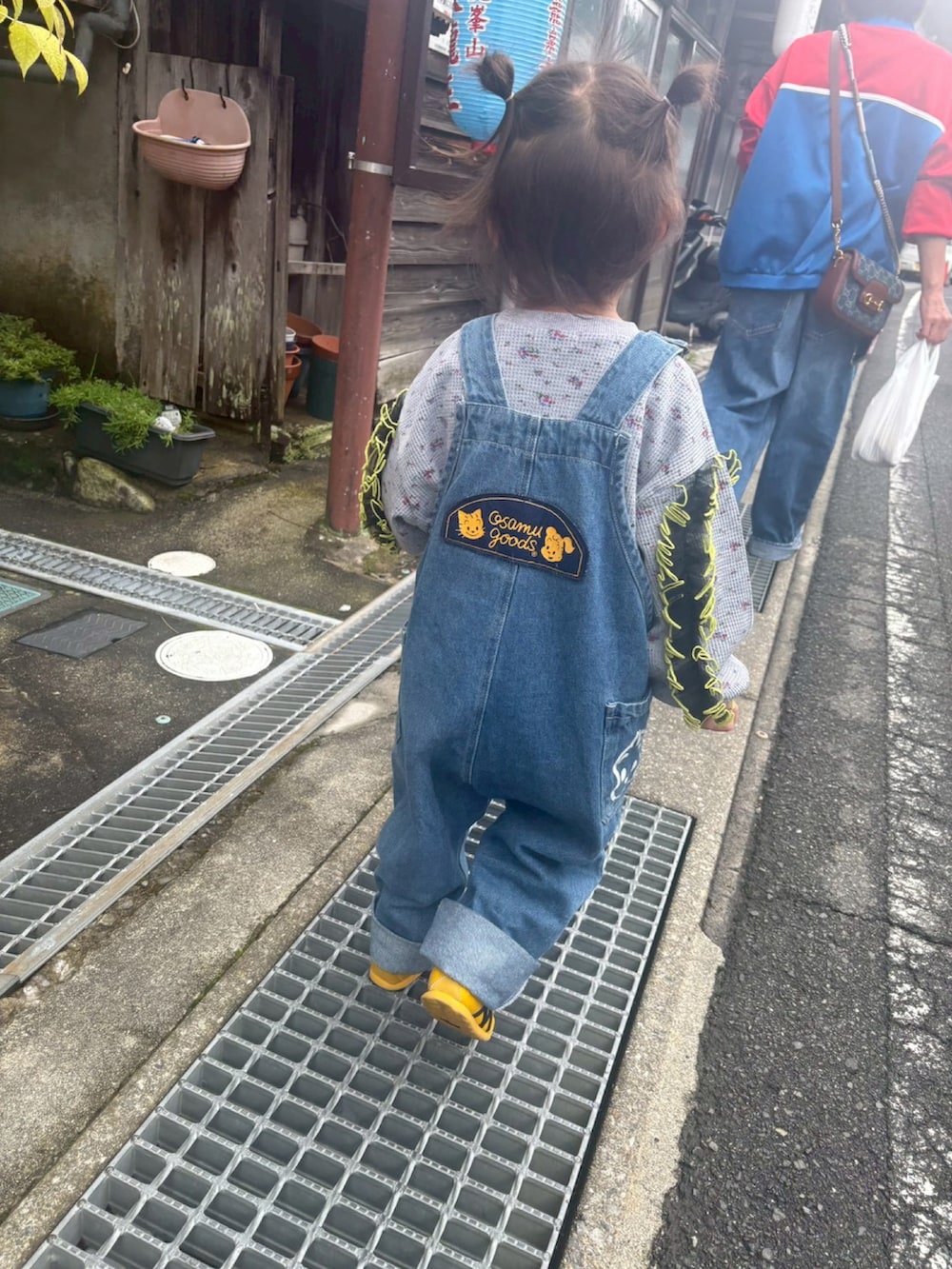 イエロー系のスニーカー、ブルー系のオールインワン・サロペット、グレー系のトップスを着用したレディースの秋コーディネートの2枚目の写真