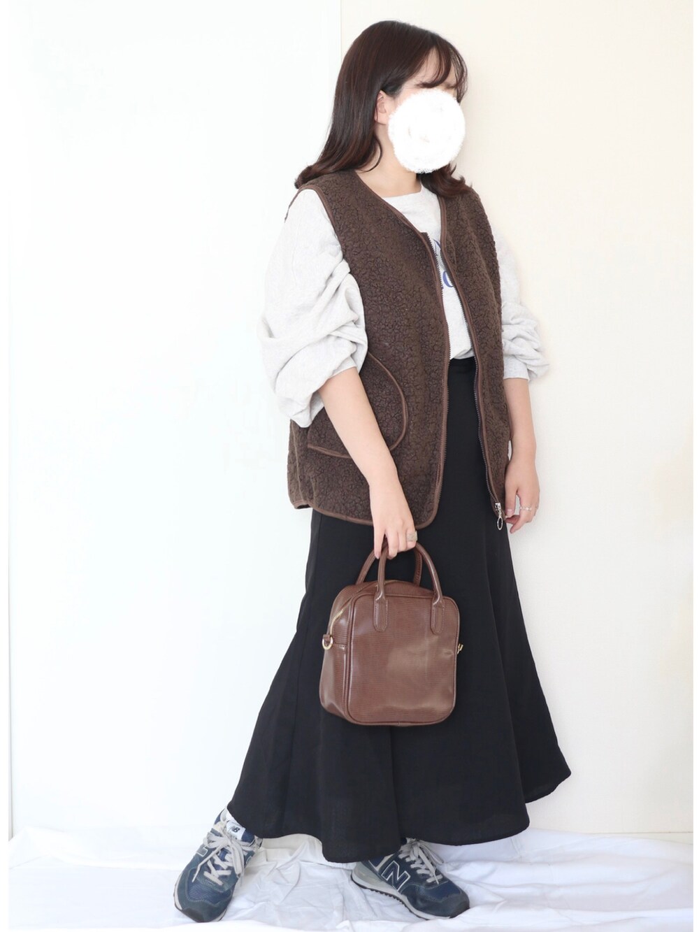 ブラウン系のベスト、グレー系のスウェット、ブラック系のスカートを着用したレディースの秋コーディネートの2枚目の写真