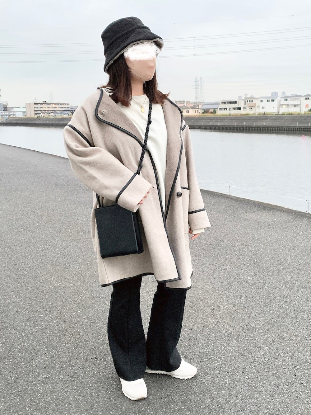 ホワイト系のスウェット、ブラック系のショルダーバッグ、ブラック系のパンツを着用したレディースの冬コーディネートの3枚目の写真