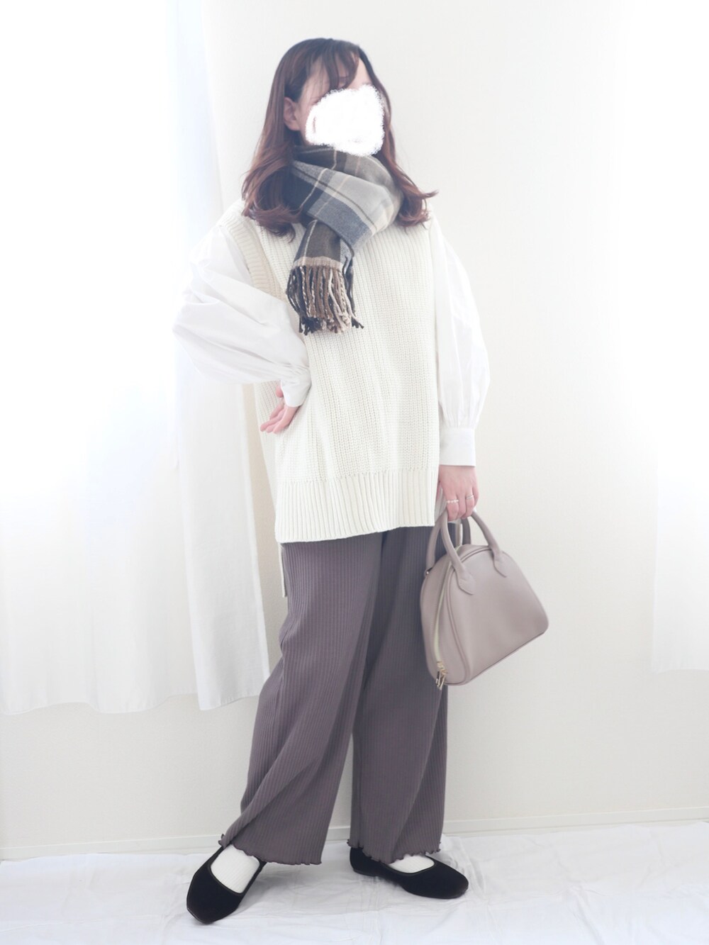 ホワイト系のベスト、ベージュ系のハンドバッグ、ブラウン系のパンツを着用したレディースの冬コーディネートの3枚目の写真