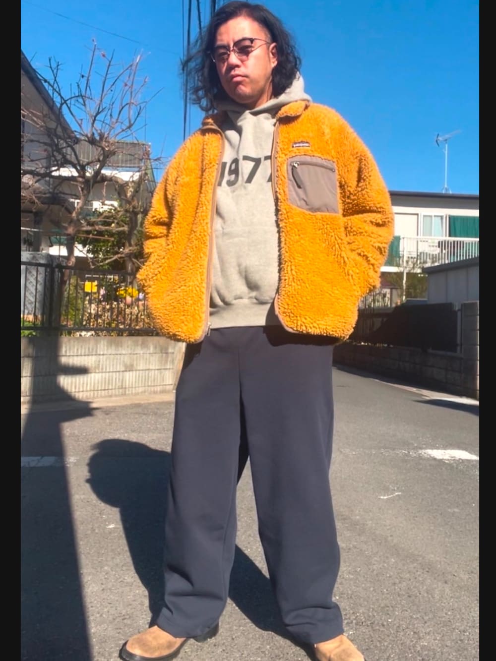 ゴールド系のジャケット/アウター、グレー系のパーカー、ブルー系のスウェットパンツを着用したメンズの冬コーディネートの2枚目の写真