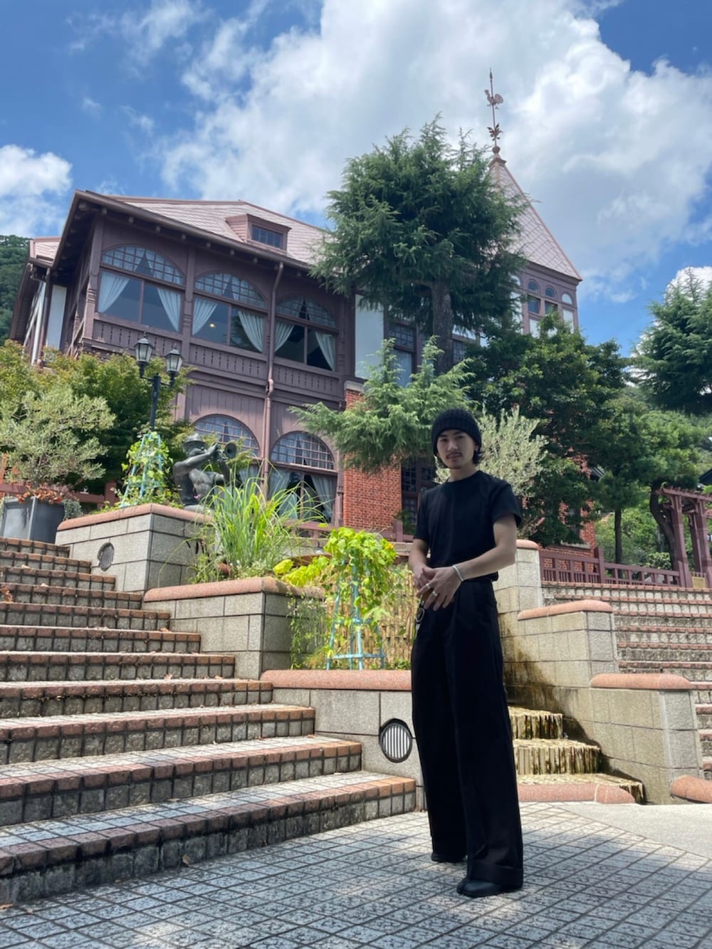 ブラック系のTシャツ/カットソー、ブラック系のスラックス、ブラック系のブーツを着用したメンズの夏コーディネートの4枚目の写真