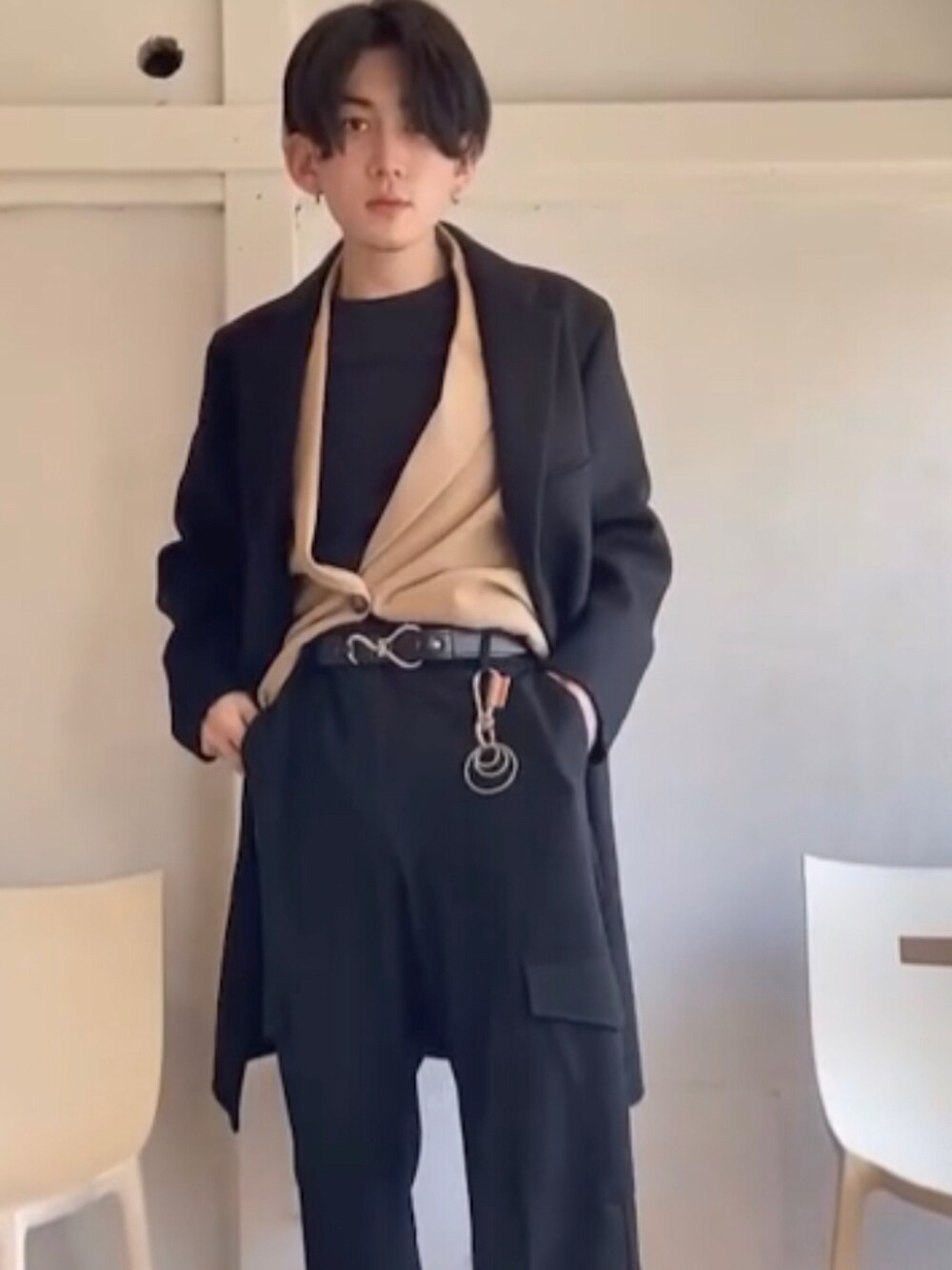 ブラック系のノーカラーコート、ベージュ系のベスト、ブラック系のスラックスを着用したメンズの冬コーディネートの4枚目の写真