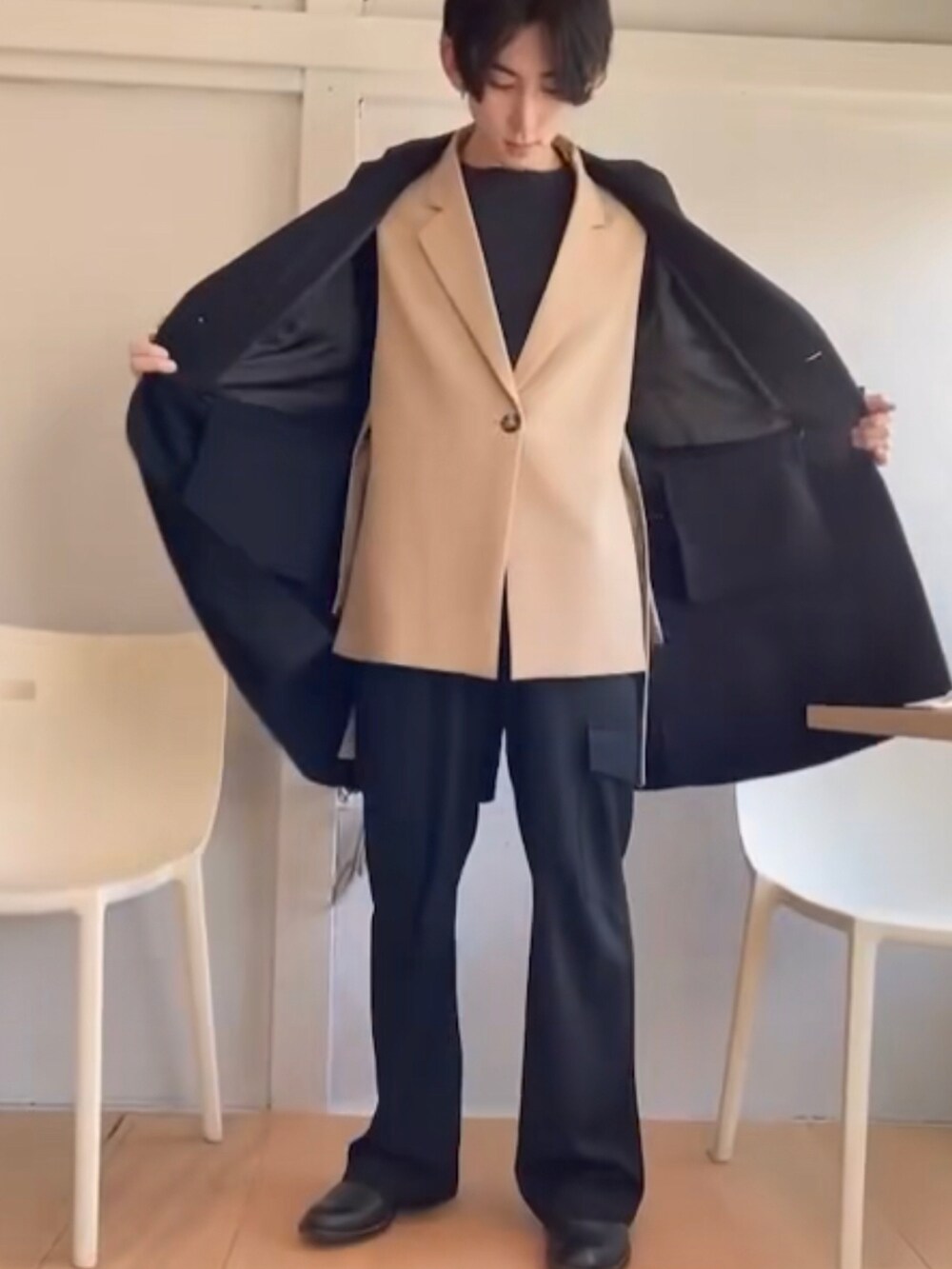 ブラック系のノーカラーコート、ベージュ系のベスト、ブラック系のスラックスを着用したメンズの冬コーディネートの3枚目の写真