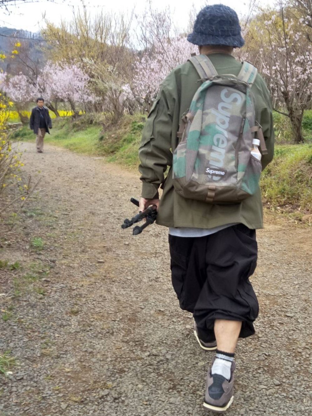 グリーン系のミリタリージャケット、グリーン系のカーゴパンツ、パープル系のスニーカーを着用したメンズの春コーディネートの2枚目の写真