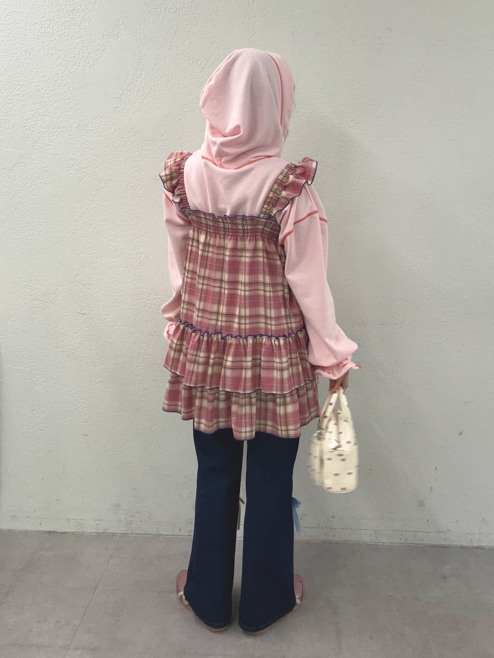 ピンク系のパーカー、ピンク系のワンピース、ブルー系のデニムパンツを着用したレディースの春コーディネートの2枚目の写真