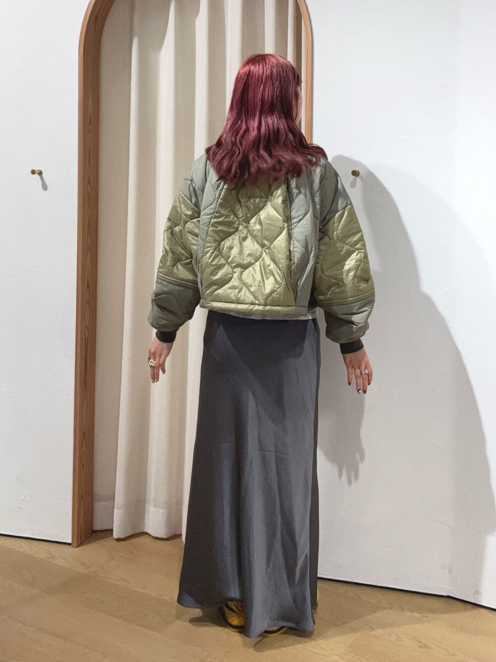 グリーン系のブルゾン、グレー系のスカートを着用したレディースの秋コーディネートの3枚目の写真