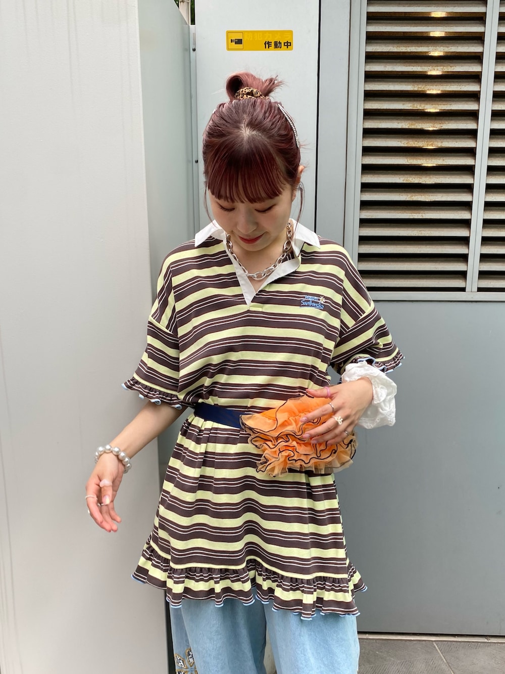 イエロー系のチュニック、オレンジ系のボディバッグ/ウエストポーチ、ブルー系のデニムパンツを着用したレディースの秋コーディネートの2枚目の写真