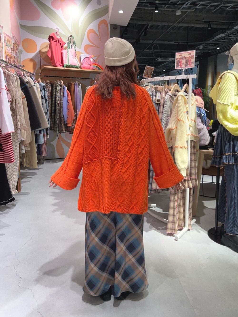 オレンジ系のニット/セーター、ベージュ系のスカートを着用したレディースの冬コーディネートの2枚目の写真