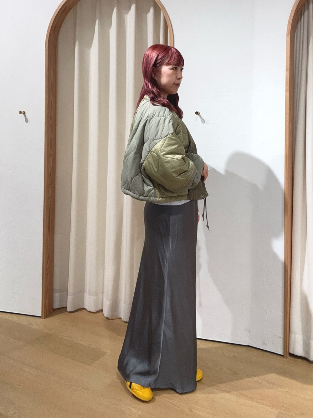 グリーン系のブルゾン、グレー系のスカートを着用したレディースの秋コーディネートの2枚目の写真