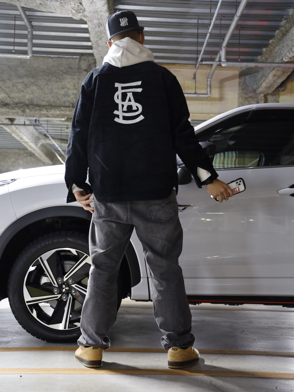 グレー系のデニムパンツ、ホワイト系のパーカー、ブラック系のその他アウターを着用したメンズの冬コーディネートの2枚目の写真