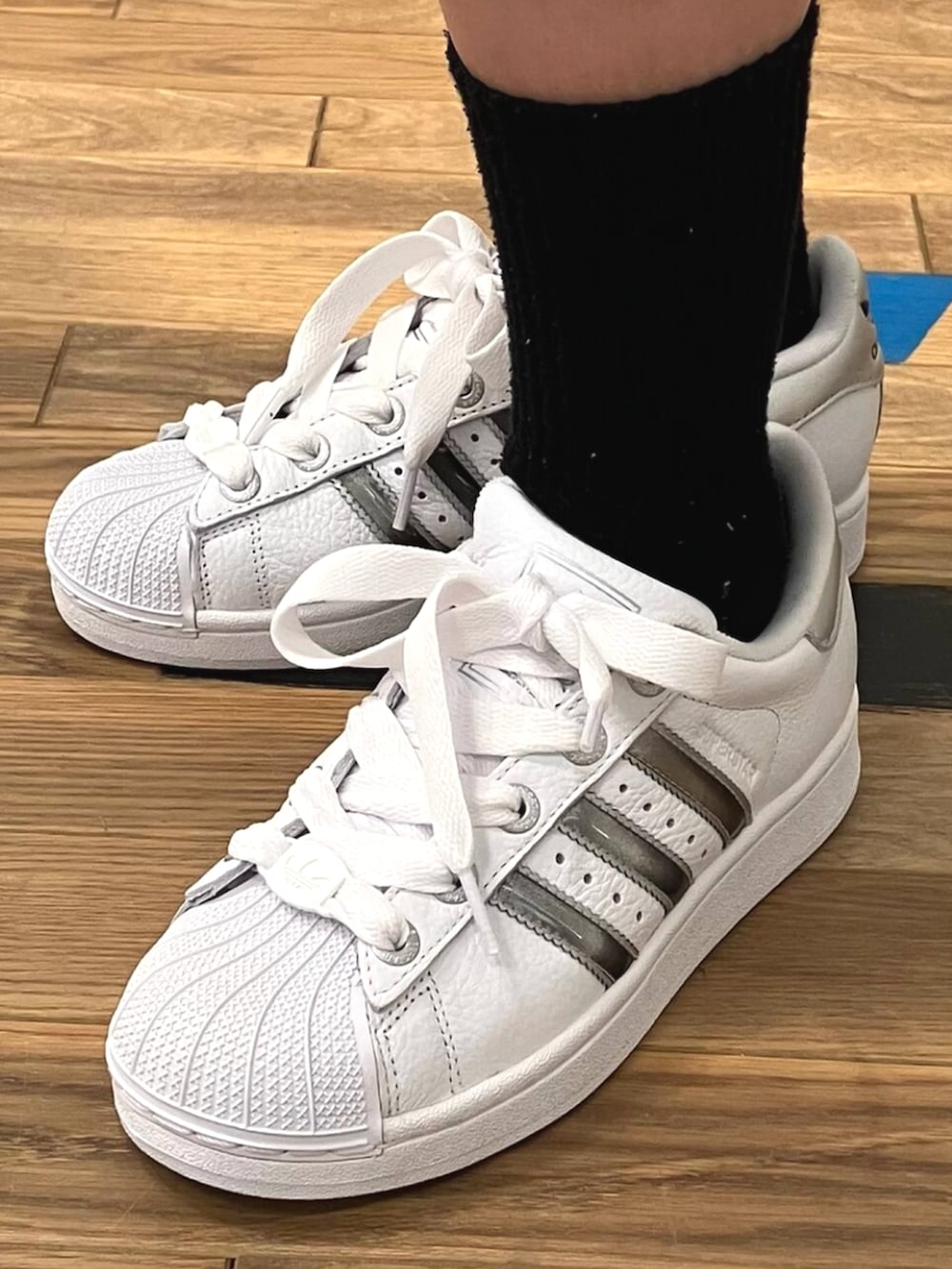 ホワイト系のスニーカー、ブラック系のナイロンジャケット、ホワイト系のタンクトップを着用したレディースの夏コーディネートの4枚目の写真