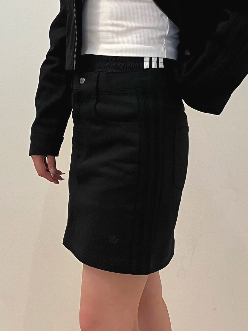 ホワイト系のスニーカー、ブラック系のナイロンジャケット、ホワイト系のタンクトップを着用したレディースの夏コーディネートの3枚目の写真