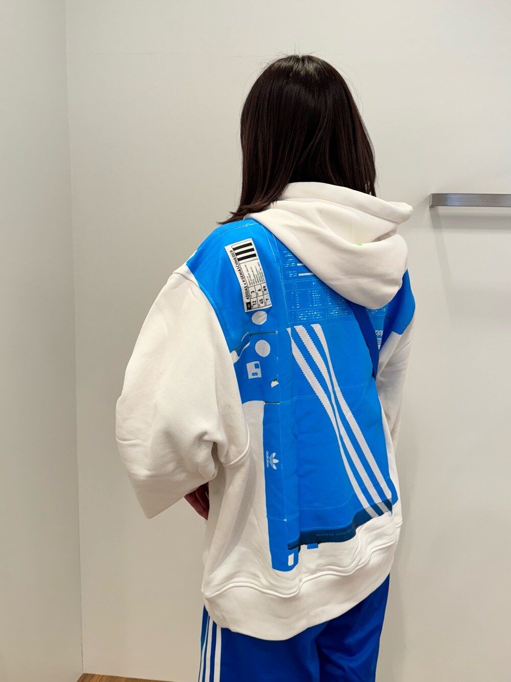 ホワイト系のスニーカー、ブルー系のショルダーバッグ、ホワイト系のトップスを着用したレディースの冬コーディネートの6枚目の写真