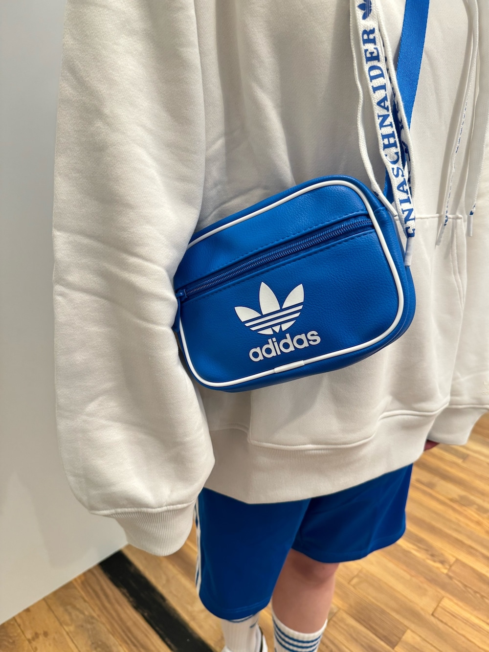 ホワイト系のスニーカー、ブルー系のショルダーバッグ、ホワイト系のトップスを着用したレディースの冬コーディネートの4枚目の写真