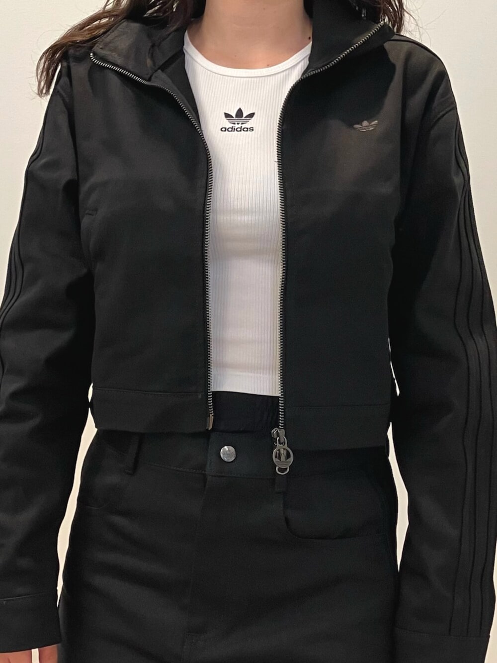 ホワイト系のスニーカー、ブラック系のナイロンジャケット、ホワイト系のタンクトップを着用したレディースの夏コーディネートの2枚目の写真