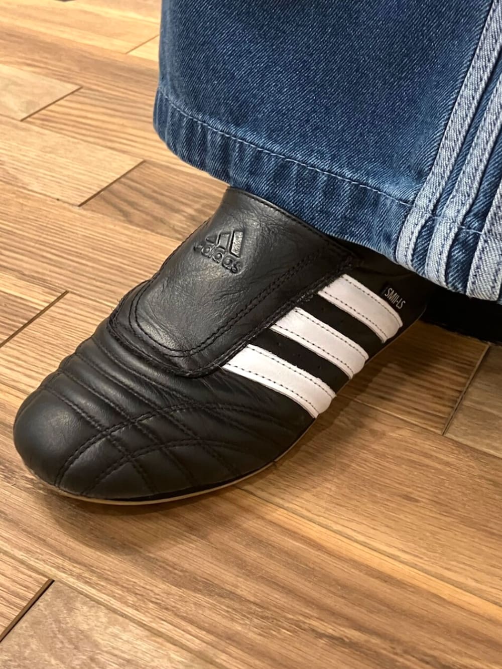 ブラック系のシューズ、イエロー系のジャージ、ブルー系のデニムパンツを着用したレディースの秋コーディネートの4枚目の写真