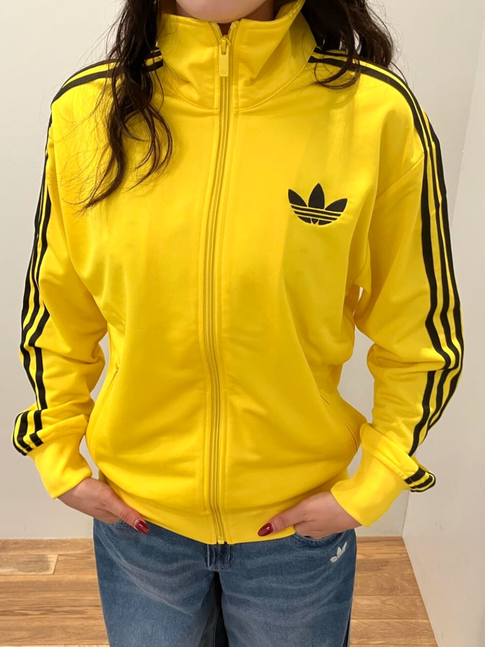 ブラック系のシューズ、イエロー系のジャージ、ブルー系のデニムパンツを着用したレディースの秋コーディネートの2枚目の写真