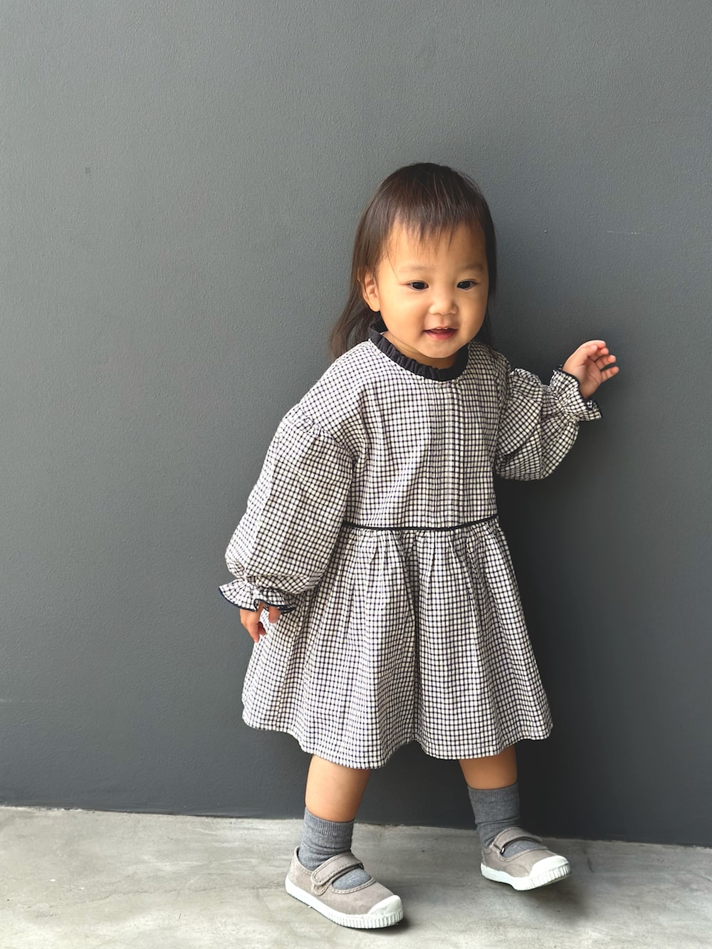 グレー系のワンピース、ブラウン系のスニーカーを着用したキッズの秋コーディネートの2枚目の写真