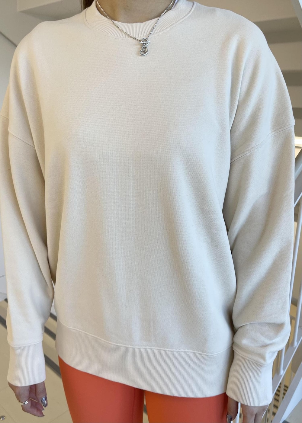 ホワイト系のスニーカー、ベージュ系のスウェット、オレンジ系のレギンス/スパッツを着用したレディースの春コーディネートの4枚目の写真