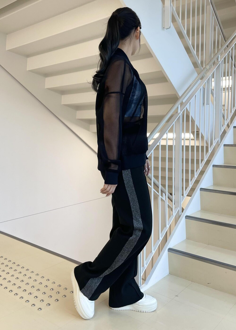 ブラック系のカーディガン/ボレロ、ホワイト系のスニーカー、ブラック系のその他パンツを着用したレディースの冬コーディネートの2枚目の写真