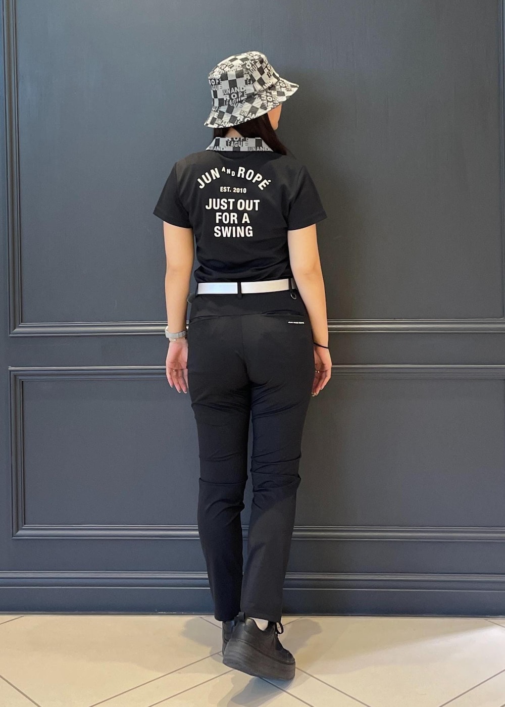 ブラック系のポロシャツ、ブラック系のトートバッグ、ブラック系のその他パンツを着用したレディースの春コーディネートの2枚目の写真