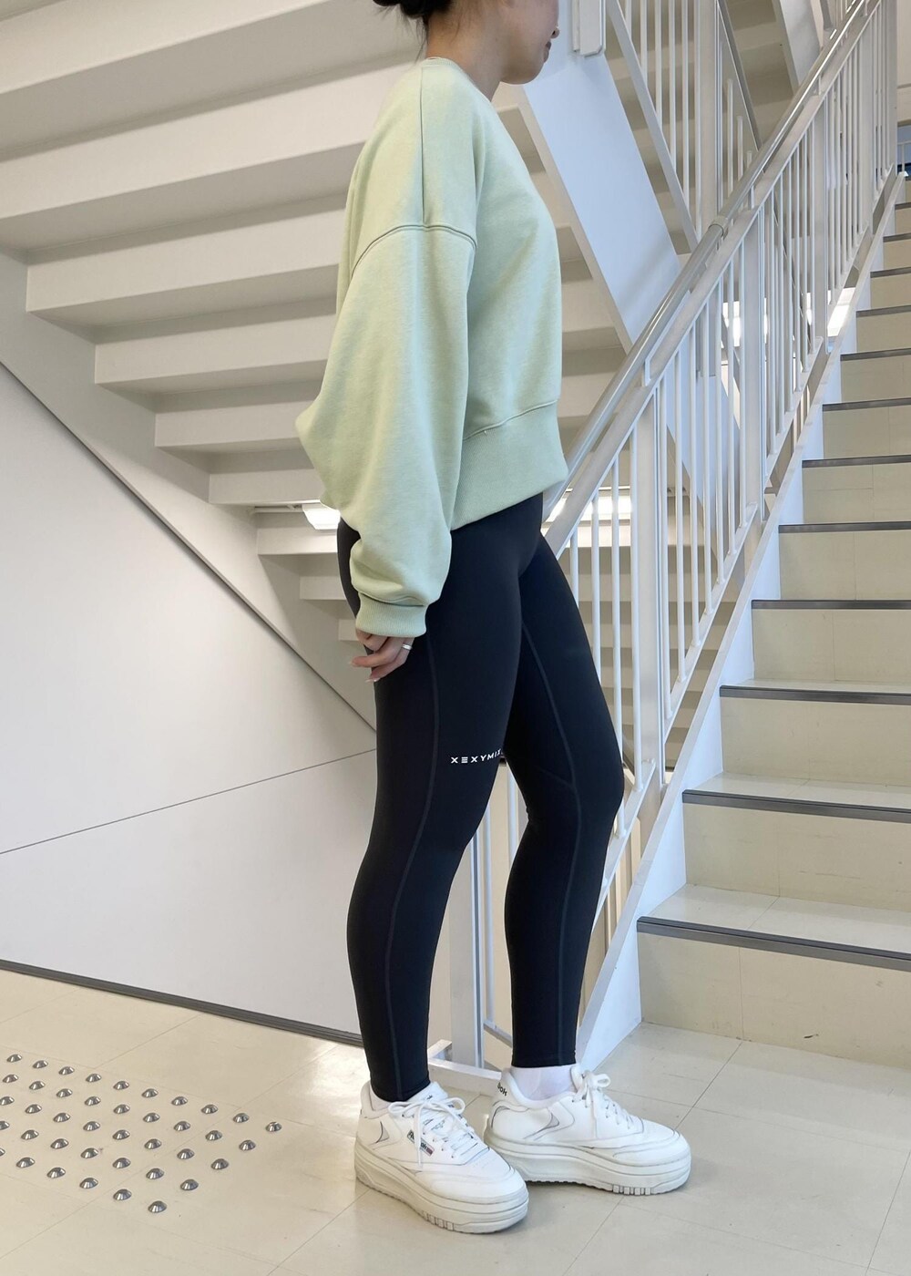 ホワイト系のスニーカー、グリーン系のスウェット、グレー系のレギンス/スパッツを着用したレディースの冬コーディネートの2枚目の写真