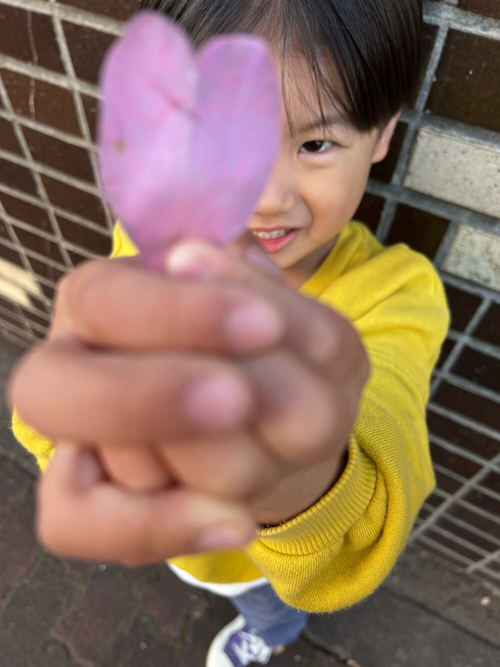ベージュ系のノーカラーコート、パープル系のスニーカー、ブルー系のパンツを着用したキッズの冬コーディネートの2枚目の写真