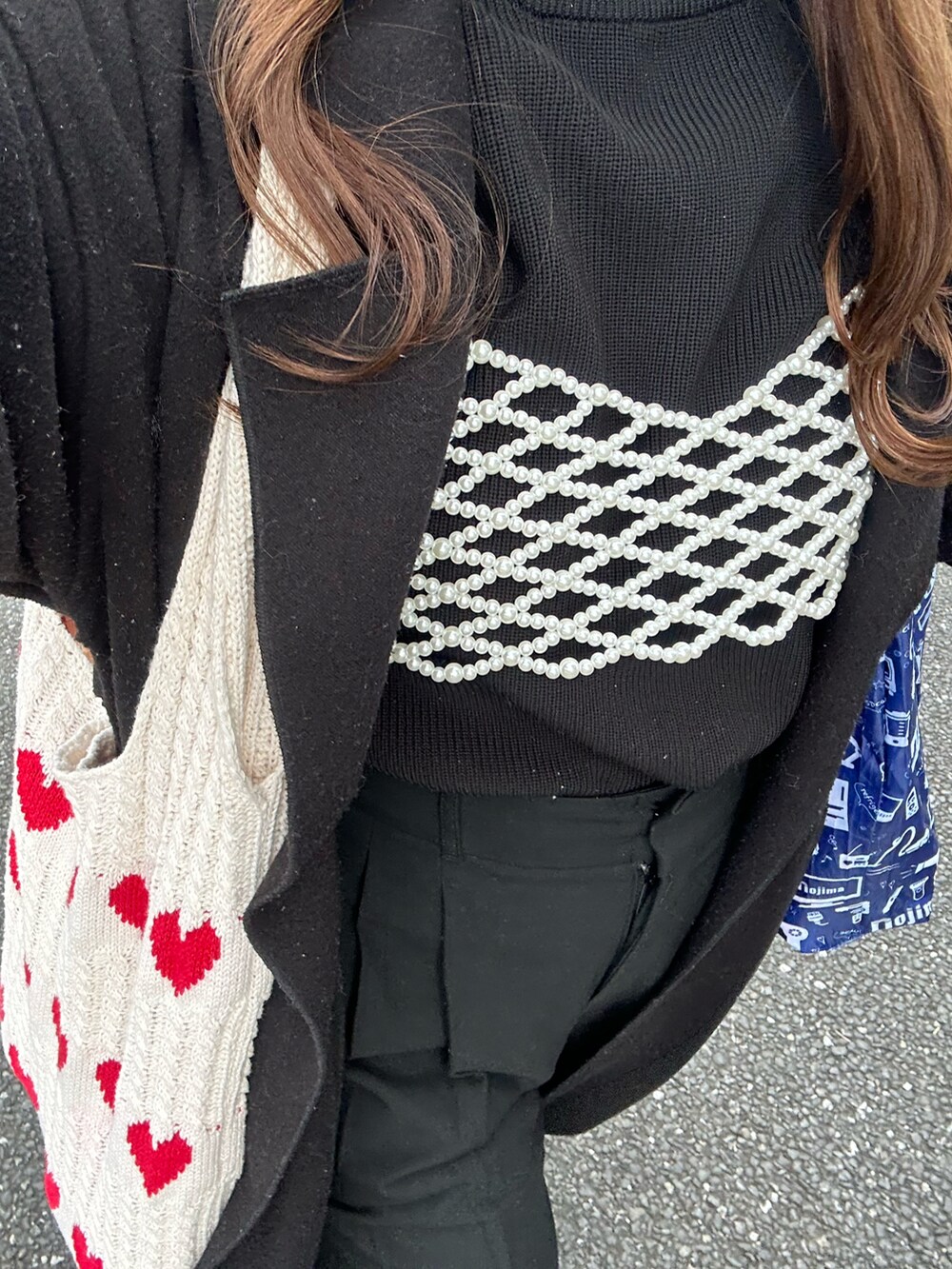 レッド系のトートバッグ、ブラック系のジャケット/アウター、ブラック系のパンツを着用したレディースの冬コーディネートの3枚目の写真