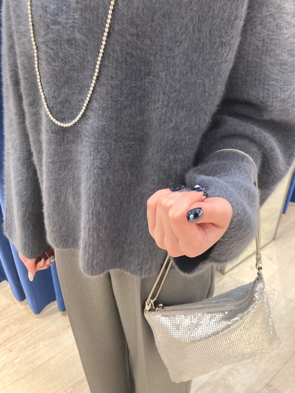 グレー系のニット/セーター、シルバー系のクラッチバッグ、グレー系のその他パンツを着用したレディースの冬コーディネートの4枚目の写真