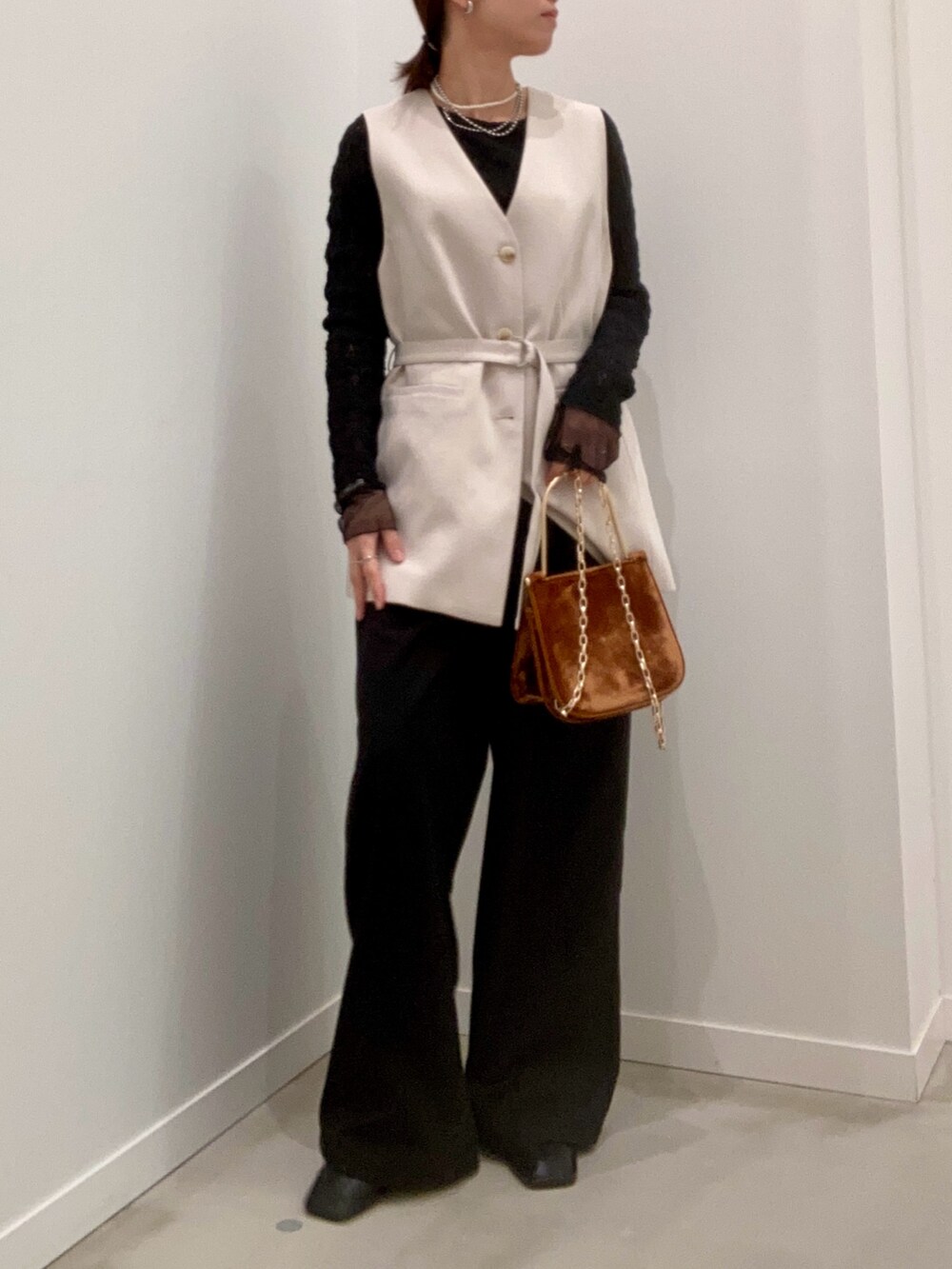 ベージュ系のベスト、ブラック系のTシャツ/カットソー、ブラウン系のショルダーバッグを着用したレディースの冬コーディネートの8枚目の写真