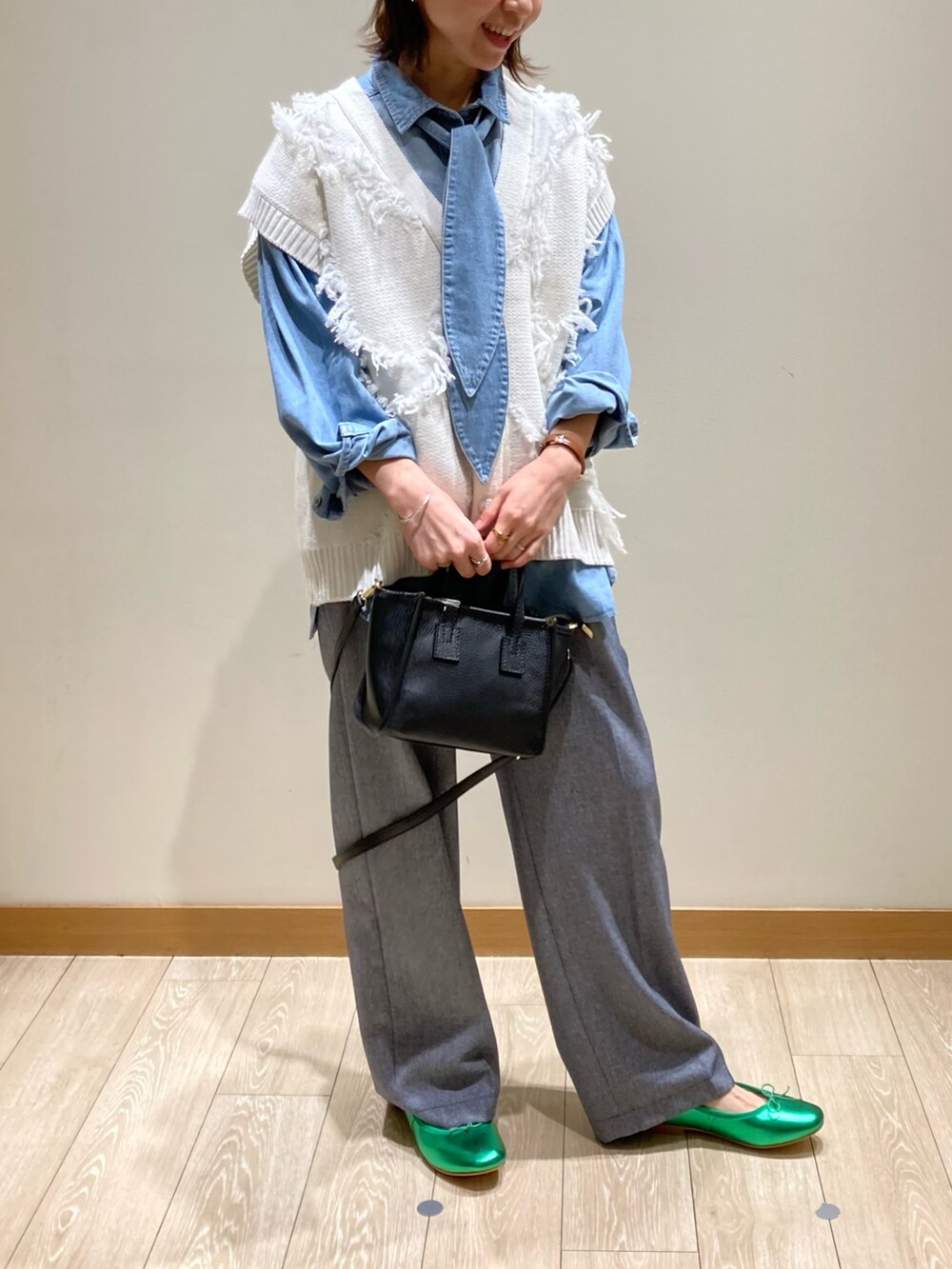 ブラック系のトートバッグ、ブルー系のスラックス、グリーン系のバレエシューズを着用したレディースの冬コーディネートの2枚目の写真