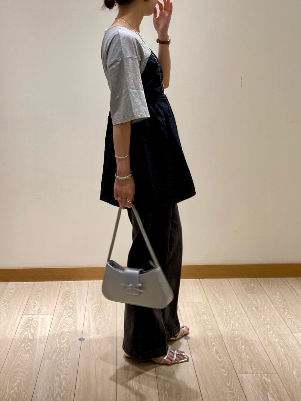 シルバー系のハンドバッグ、グレー系のTシャツ/カットソー、シルバー系のサンダルを着用したレディースの夏コーディネートの2枚目の写真