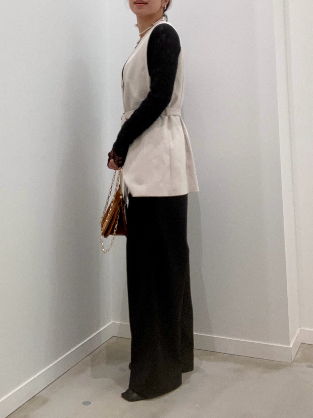 ベージュ系のベスト、ブラック系のTシャツ/カットソー、ブラウン系のショルダーバッグを着用したレディースの冬コーディネートの7枚目の写真