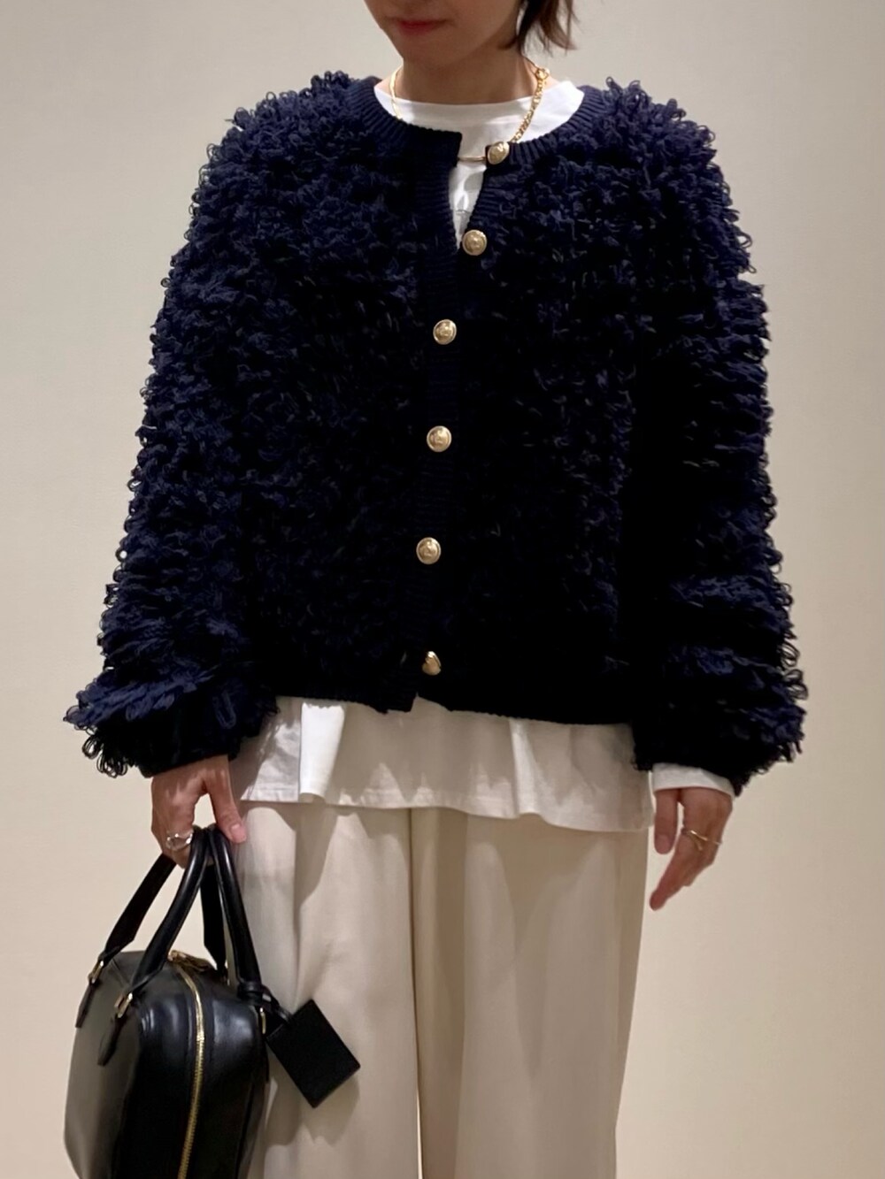 ブルー系のカーディガン/ボレロ、ブラック系のハンドバッグ、ホワイト系のTシャツ/カットソーを着用したレディースの冬コーディネートの8枚目の写真