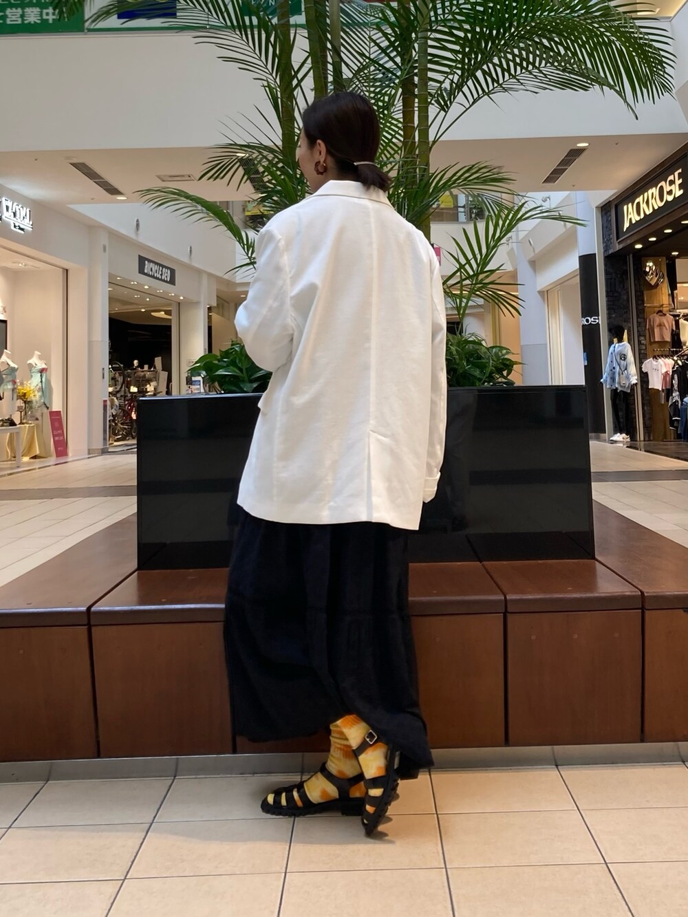 ホワイト系のテーラードジャケット、ブラック系のサンダル、ブラック系のワンピースを着用したレディースの春コーディネートの2枚目の写真