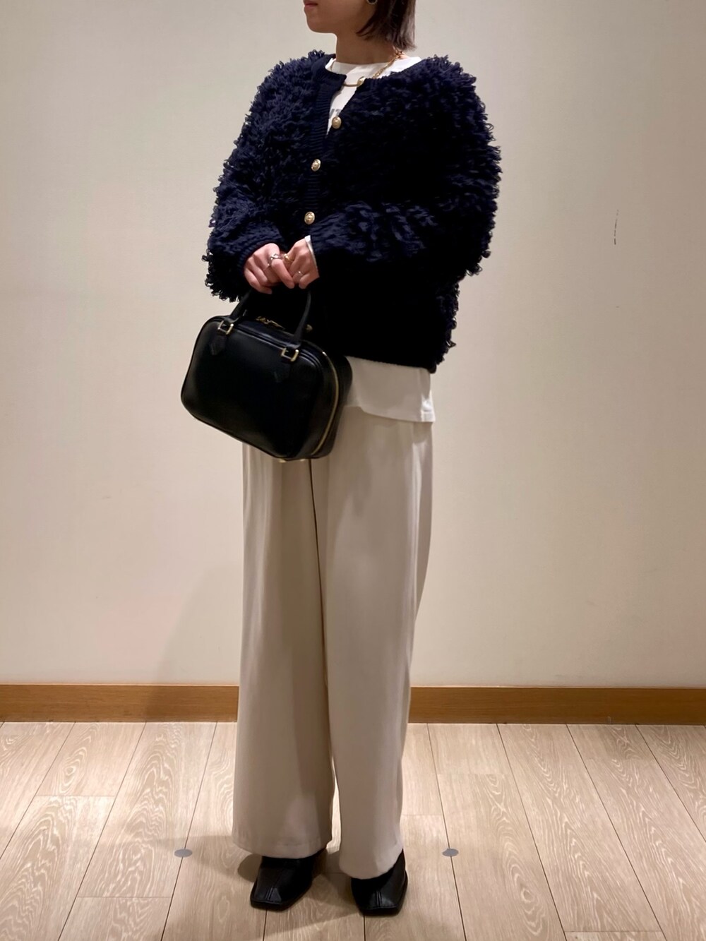 ブルー系のカーディガン/ボレロ、ブラック系のハンドバッグ、ホワイト系のTシャツ/カットソーを着用したレディースの冬コーディネートの7枚目の写真