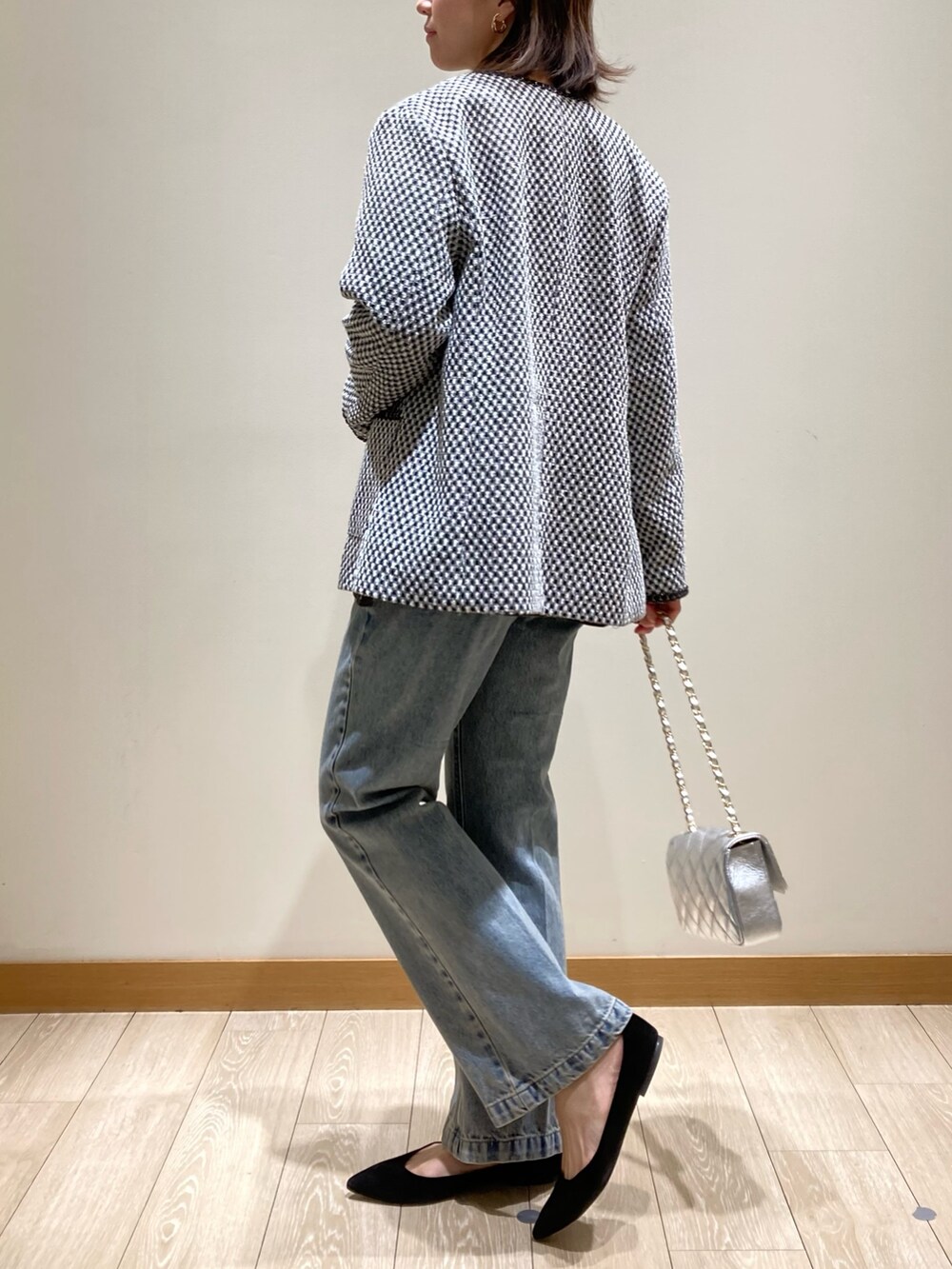 ブルー系のデニムパンツ、シルバー系のショルダーバッグ、ブラック系のノーカラージャケットを着用したレディースの冬コーディネートの5枚目の写真