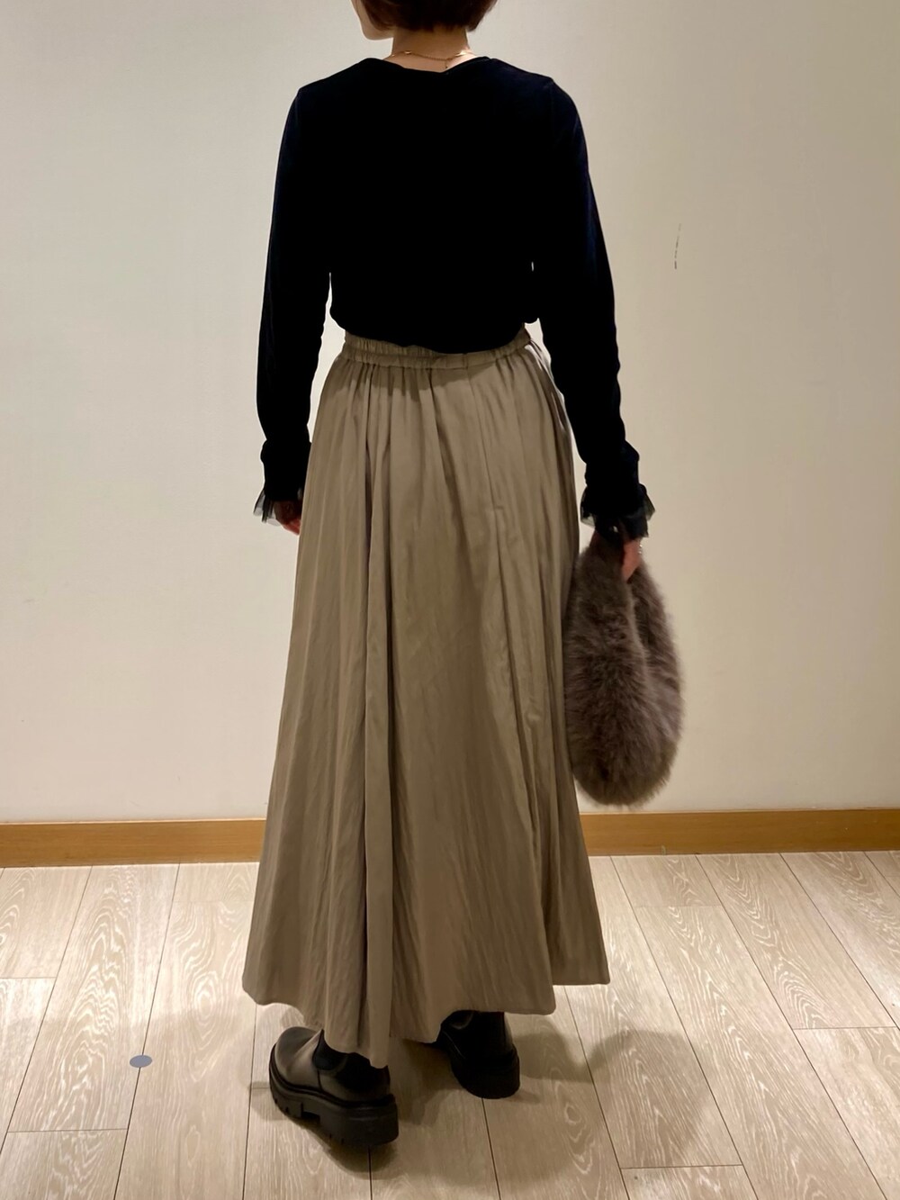 グレー系のハンドバッグ、ブラック系のブーツ、ブラック系のTシャツ/カットソーを着用したレディースの秋コーディネートの5枚目の写真