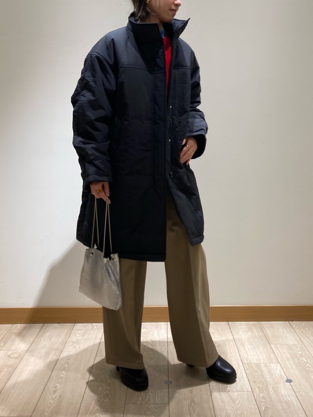 ベージュ系のスラックス、シルバー系のショルダーバッグ、ブラック系のブーツを着用したレディースの冬コーディネートの2枚目の写真