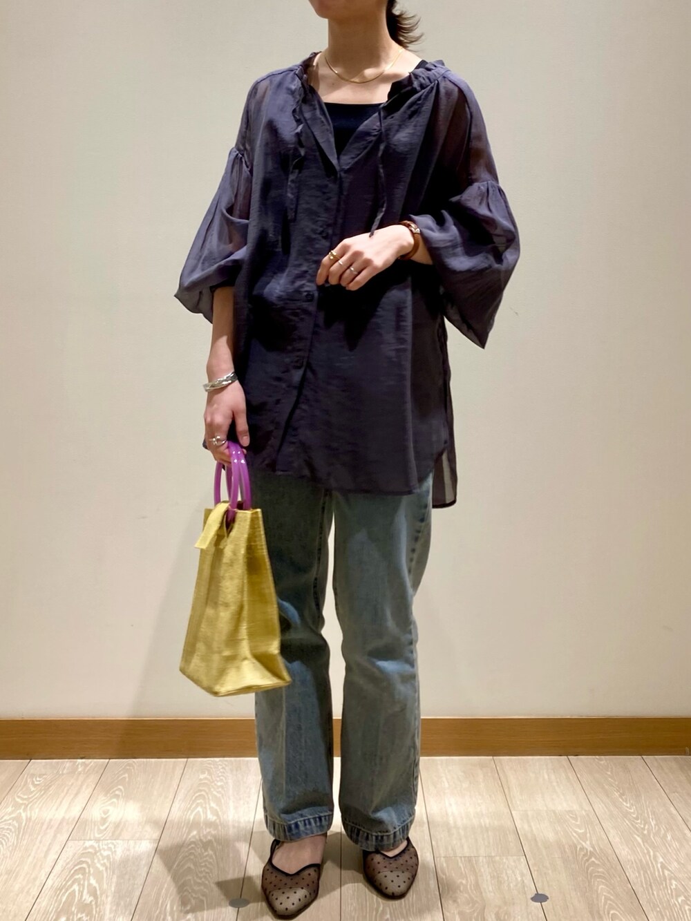 イエロー系のかごバッグ、ブルー系のデニムパンツ、ブラック系のパンプスを着用したレディースの春コーディネートの2枚目の写真