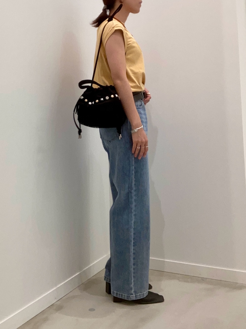 イエロー系のTシャツ/カットソー、ブルー系のデニムパンツ、ブラック系のショルダーバッグを着用したレディースの夏コーディネートの2枚目の写真