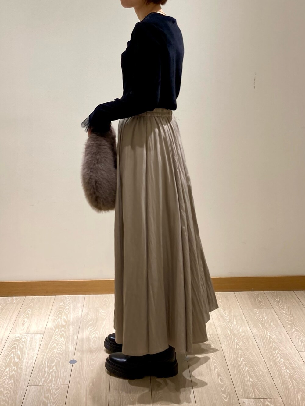 グレー系のハンドバッグ、ブラック系のブーツ、ブラック系のTシャツ/カットソーを着用したレディースの秋コーディネートの6枚目の写真