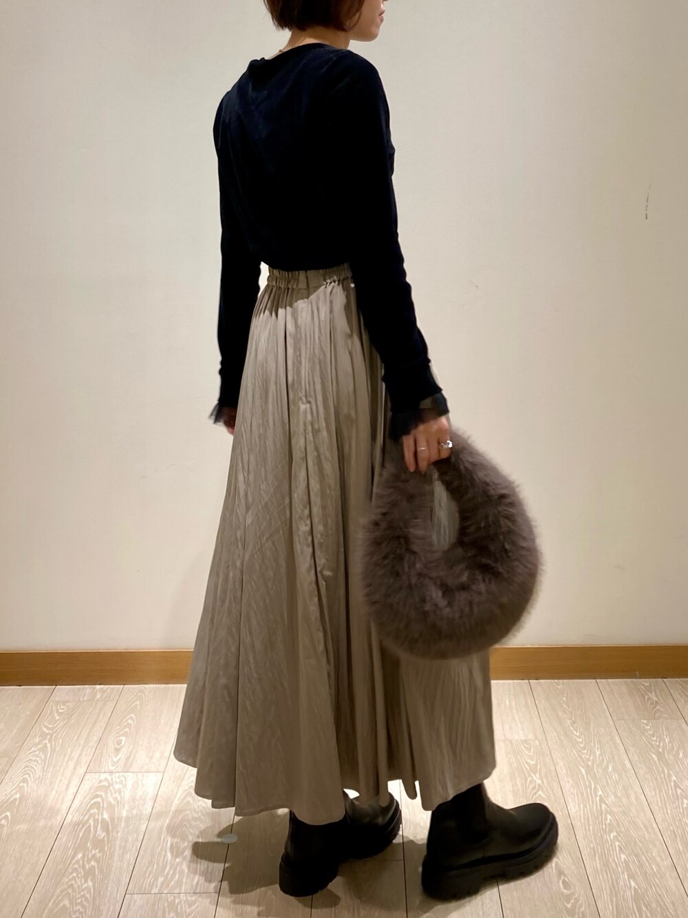 グレー系のハンドバッグ、ブラック系のブーツ、ブラック系のTシャツ/カットソーを着用したレディースの秋コーディネートの4枚目の写真