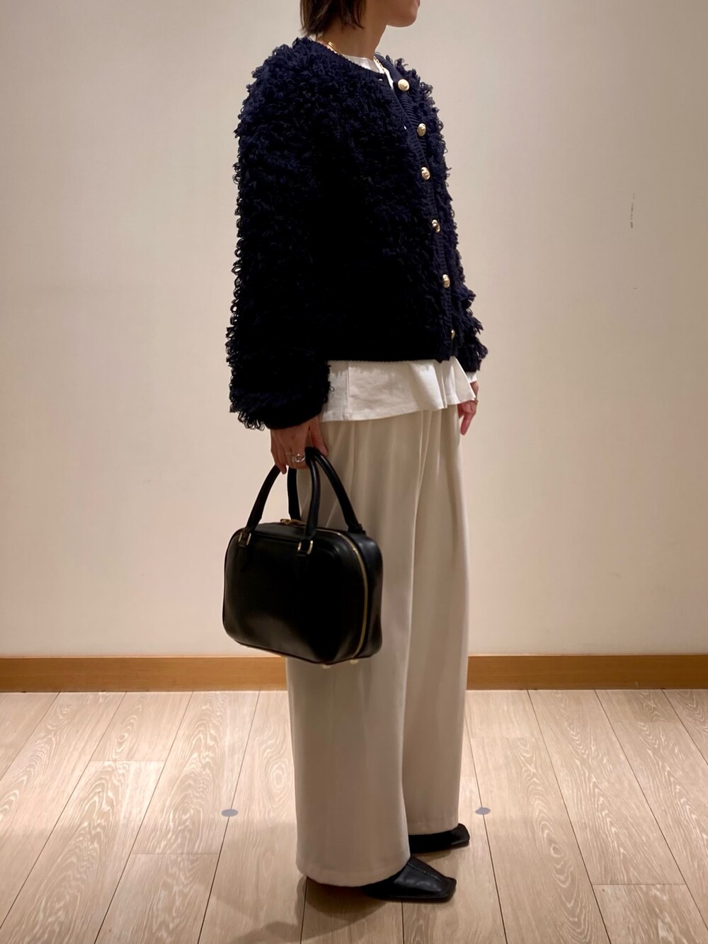 ブルー系のカーディガン/ボレロ、ブラック系のハンドバッグ、ホワイト系のTシャツ/カットソーを着用したレディースの冬コーディネートの3枚目の写真